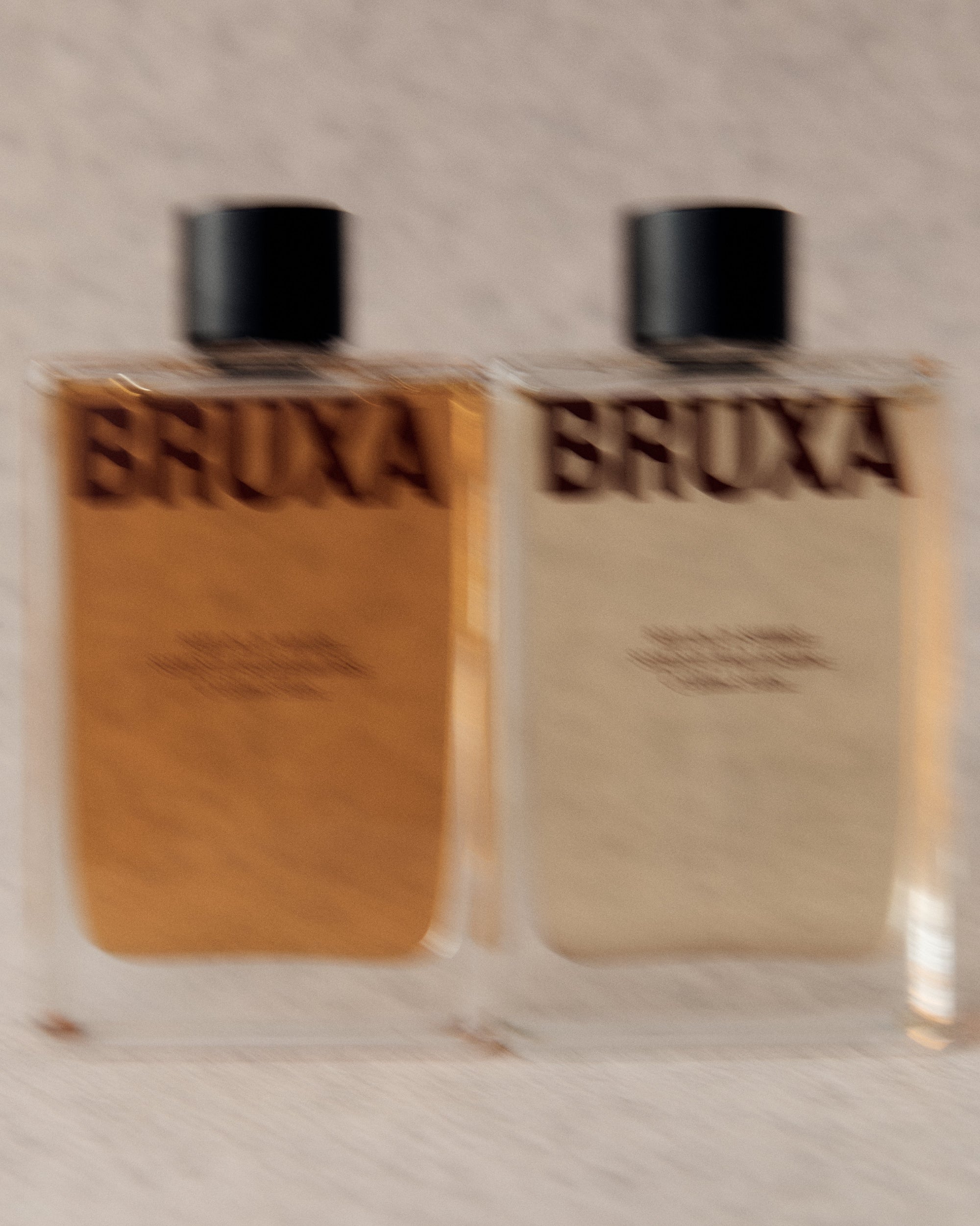 Two bottles of BRUXA on a textured surface