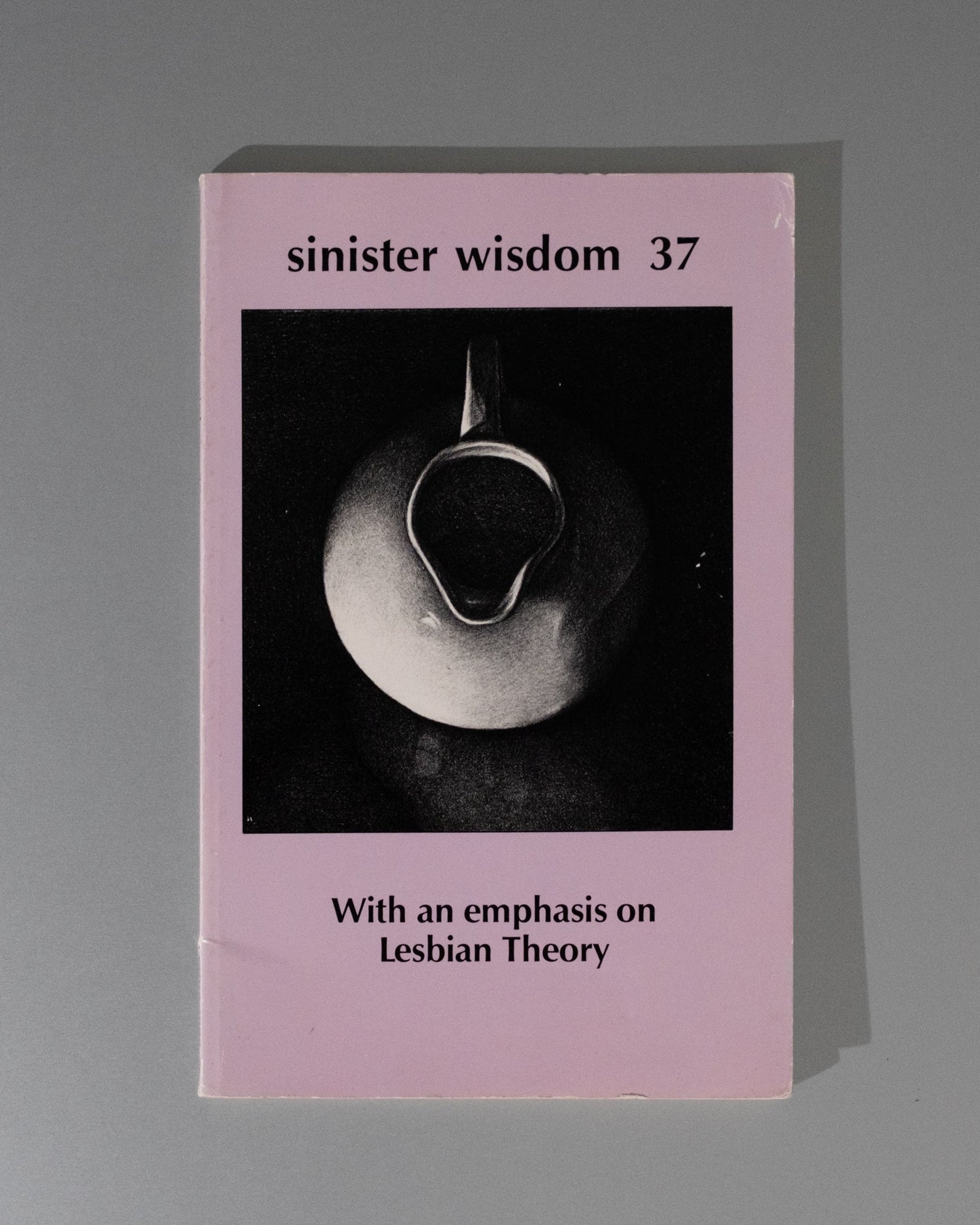 Book titled 'sinister wisdom 37' with a black and white image on a pink background