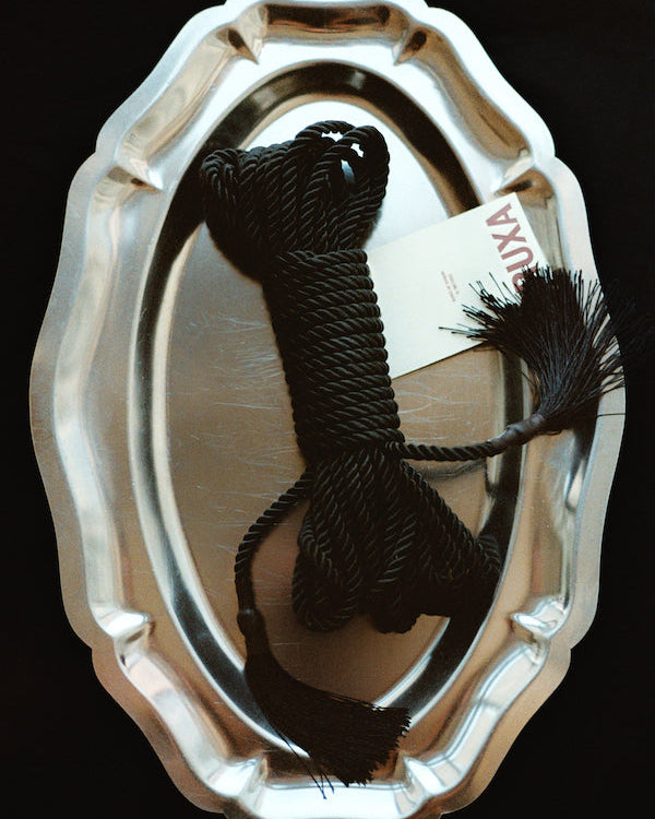 Black cord with a decorative bow on a metallic tray