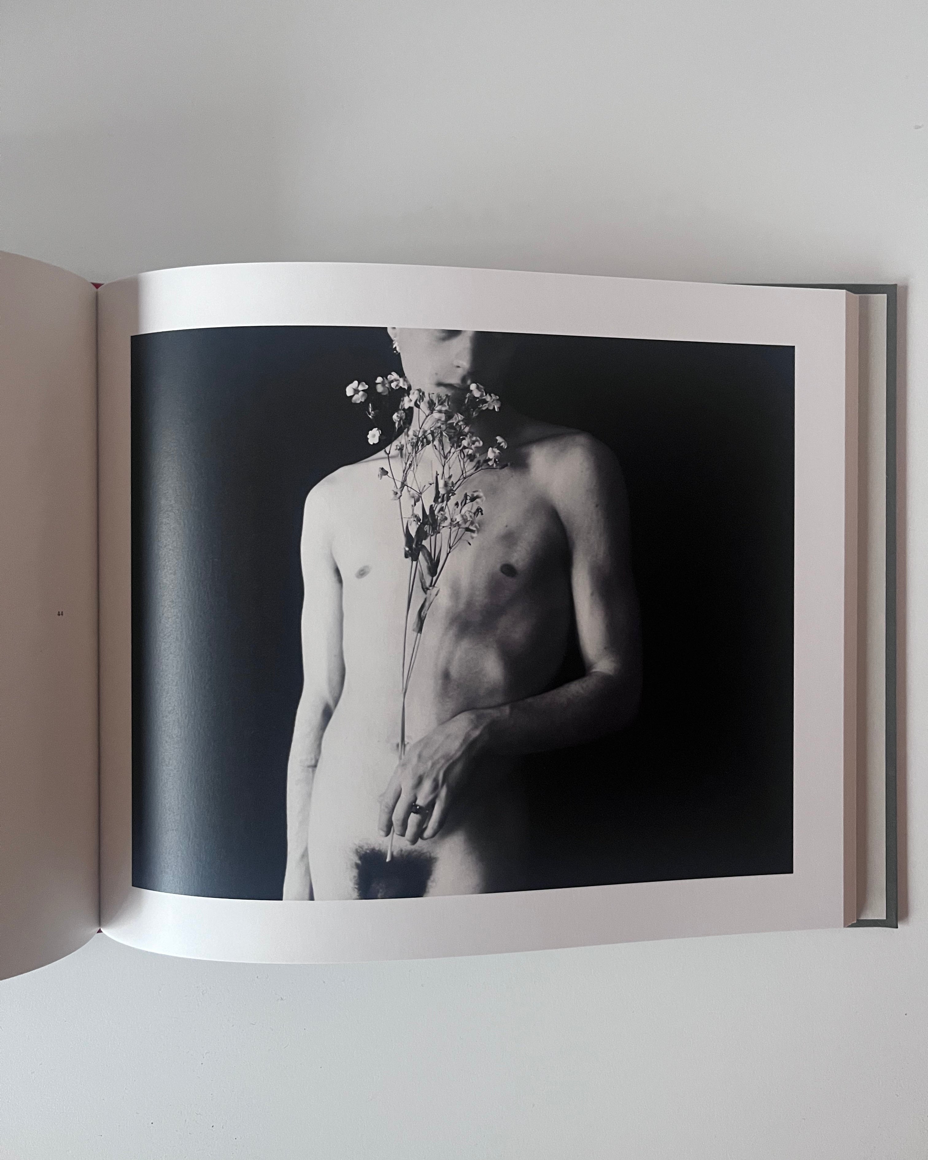 Open book showing a black and white photograph of a person with flowers on their neck.
