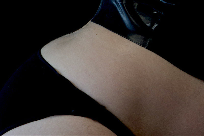 Close-up of a person wearing a black raincoat with a hood on a dark background