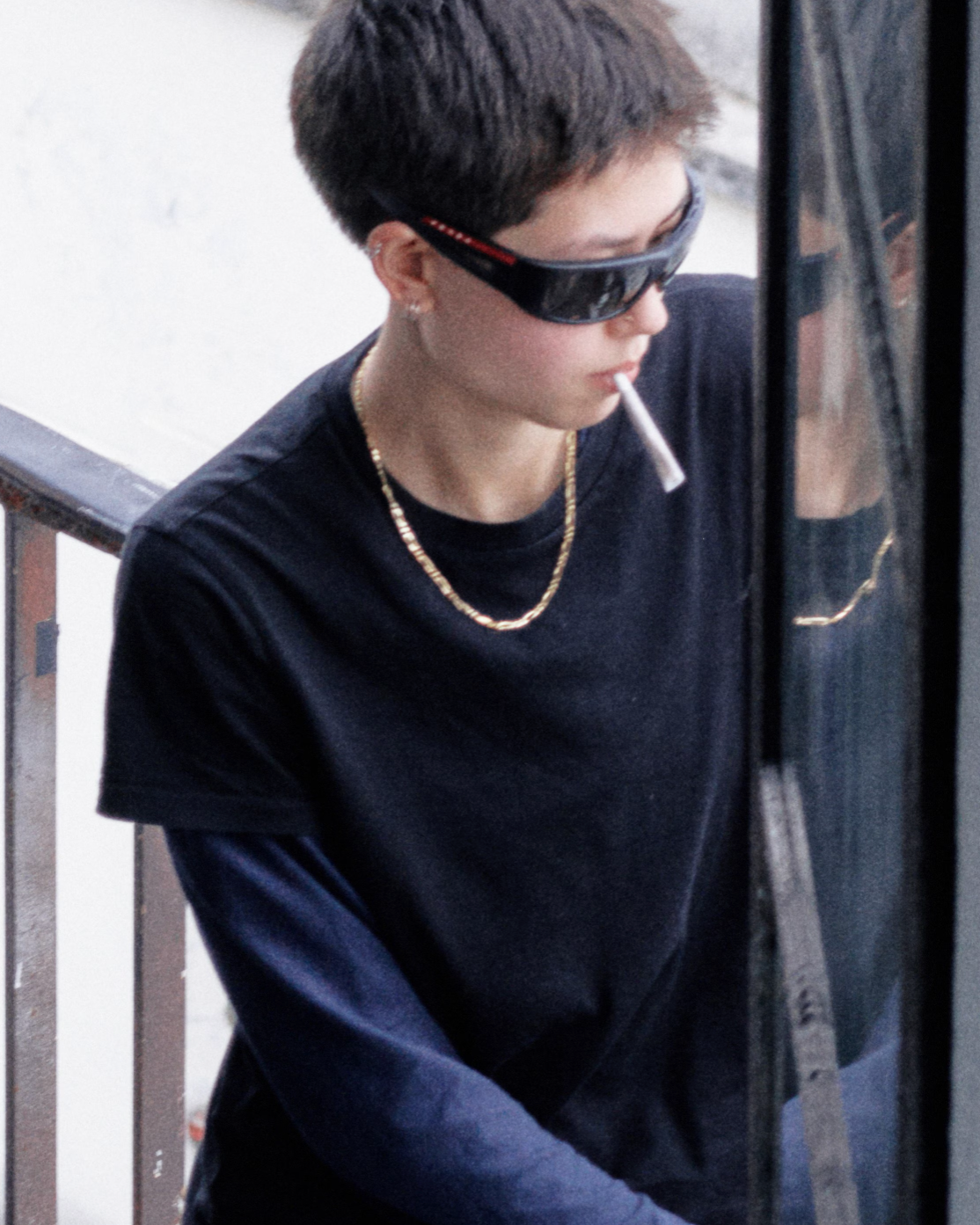 Person wearing sunglasses and a black shirt, holding a cigarette.