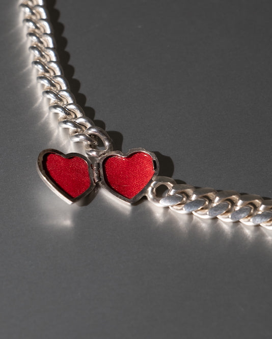 Silver chain with red heart pendants on a gray background