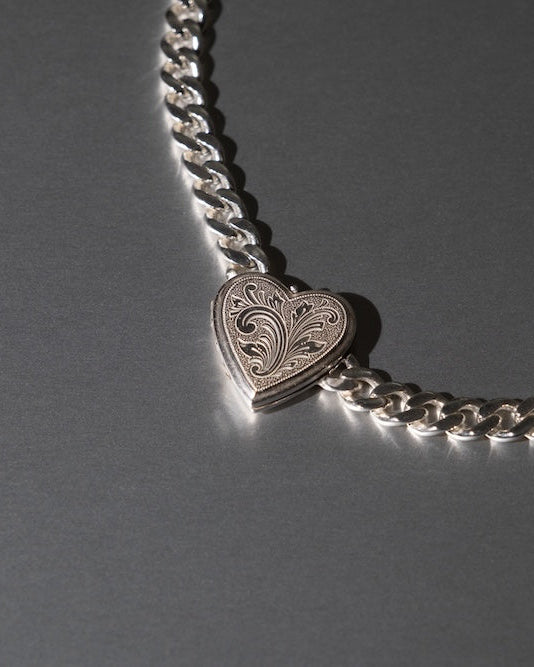 Silver chain necklace with a heart-shaped pendant on a gray background