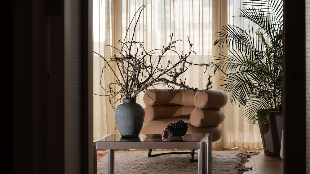 Modern living room with a beige armchair, coffee table, and decorative elements.