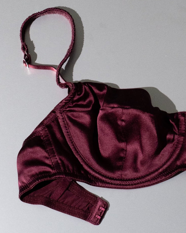Burgundy satin bra on a light gray background