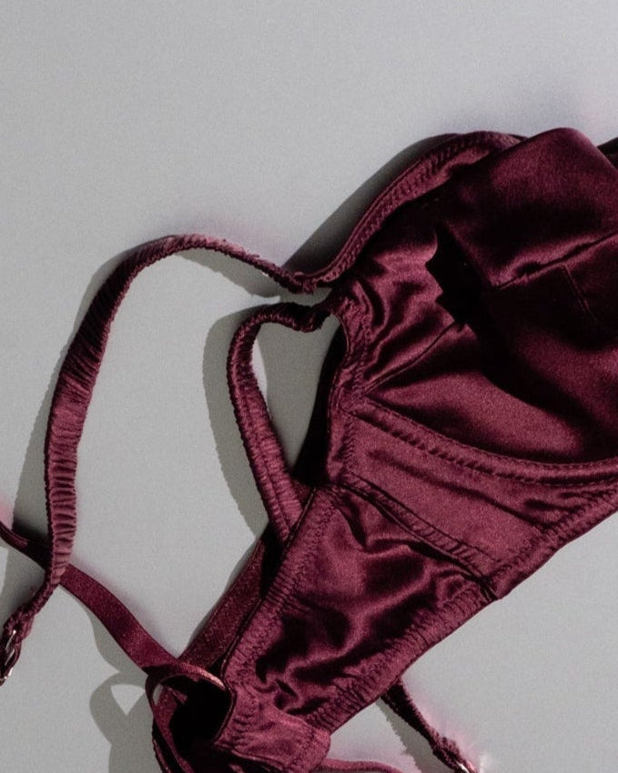 Maroon lingerie set with tags on a gray background