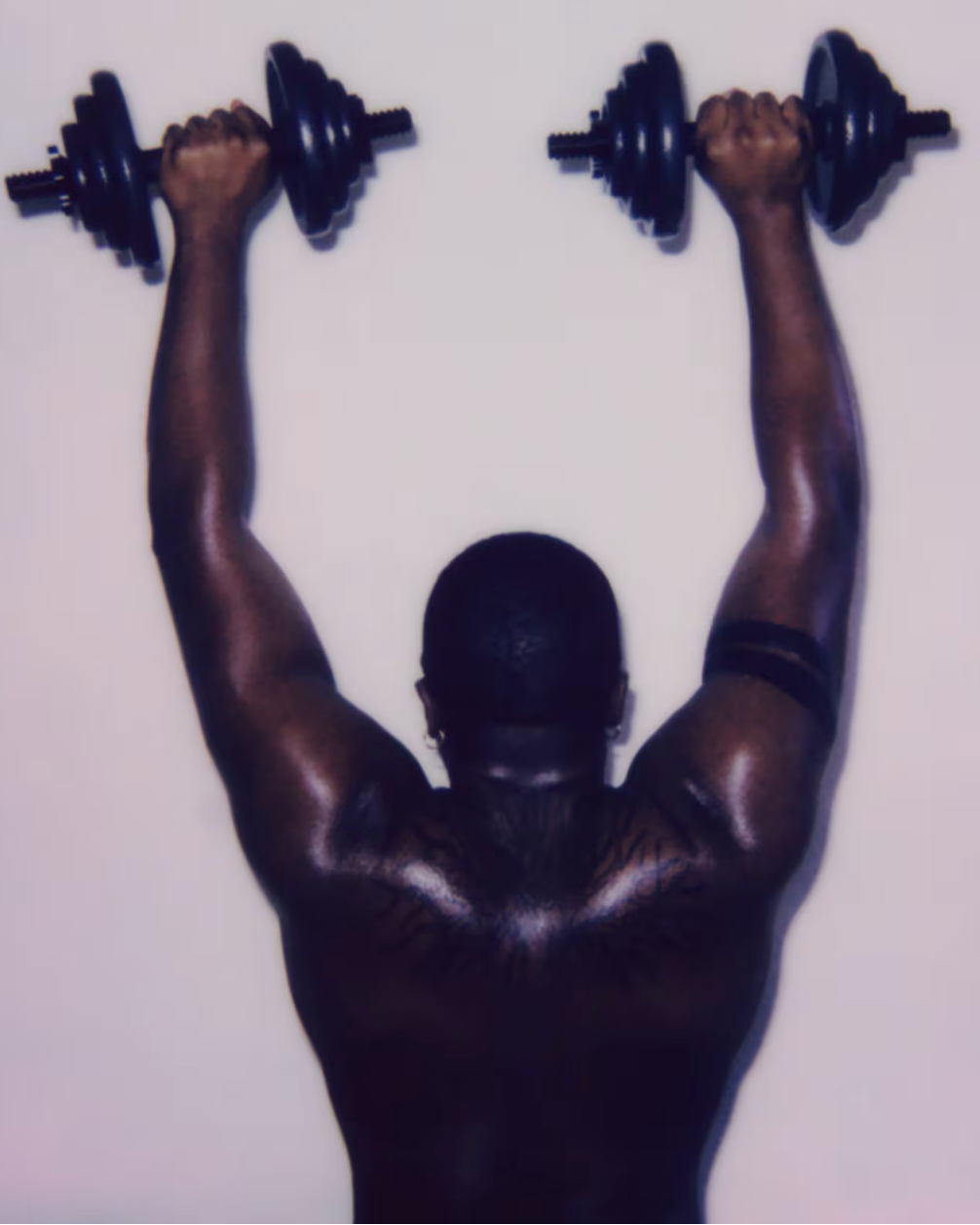Person lifting dumbbells above their head against a white background