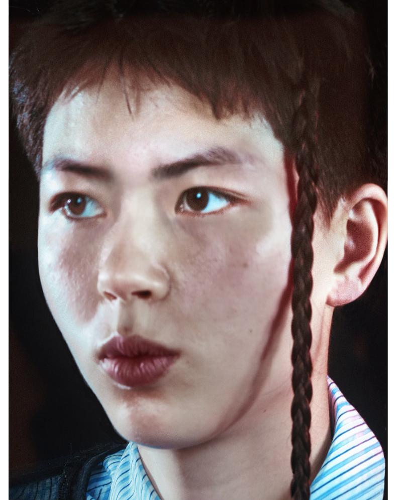 Close-up of a person with braided hair wearing a striped shirt.