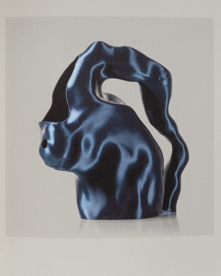 Blue ceramic sculpture on a gray background inside an open book